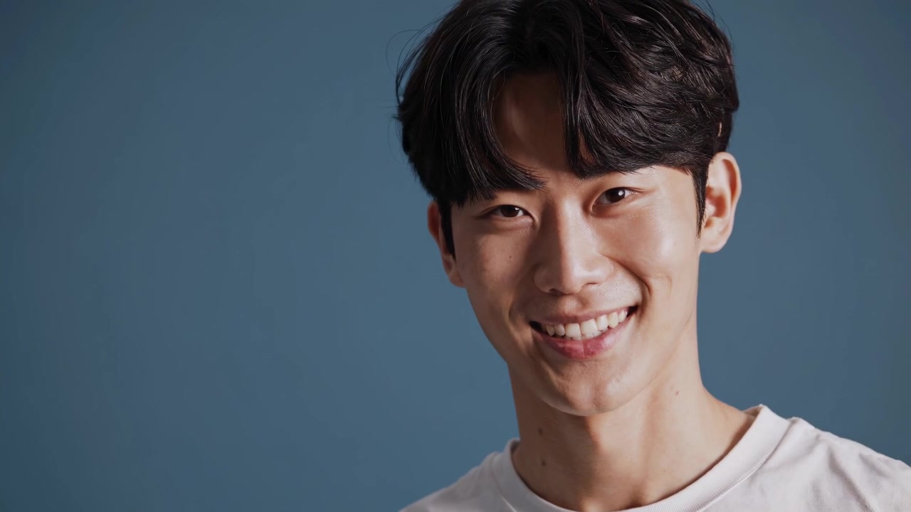 Ritratto di un giovane uomo asiatico sorridente su sfondo blu