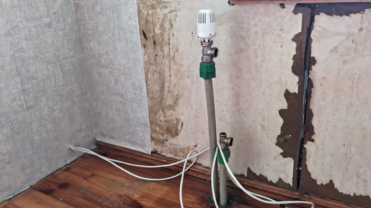 Radiator pipe exposed during room renovation with unfinished wall and wiring