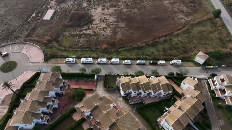 aerial birdseye view over line of various campervans parked on estartit beach waterfront