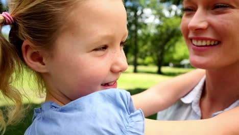 happy mother kissing her little girl in the park