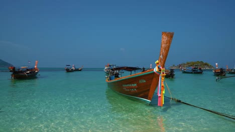 famosos, tradicionales e icónicos barcos de cola larga con flores en una playa de arena vacía en la remota isla koh lipe en tailandia, cerca de la frontera con malasia