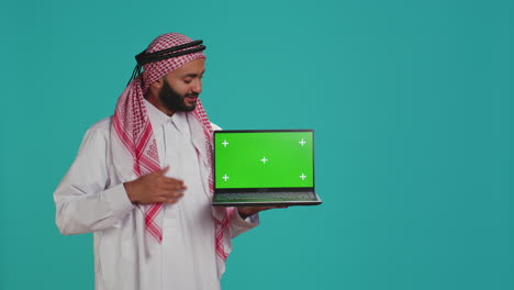 Un-Adulto-Musulmán-Muestra-Una-Computadora-Portátil-Con-Pantalla-Verde.