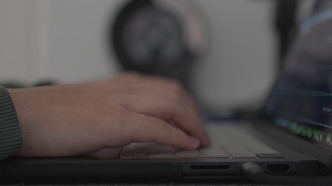 Close up of hand typing on laptop keyboard with screen glow suggesting remote work or study
