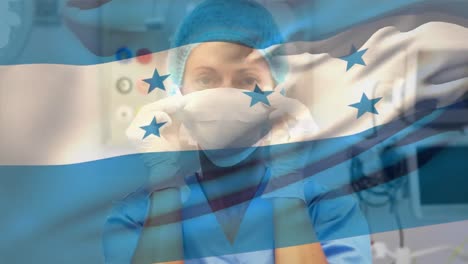 Animation-of-waving-honduras-flag-against-caucasian-female-surgeon-wearing-surgical-mask-at-hospital