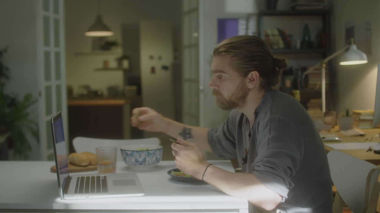 Man Having Breakfast and Using Laptop at Home