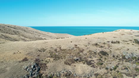 aerial reverse to reveal volcanic peninsula rocks as ocean disappears from view - banks peninsula south