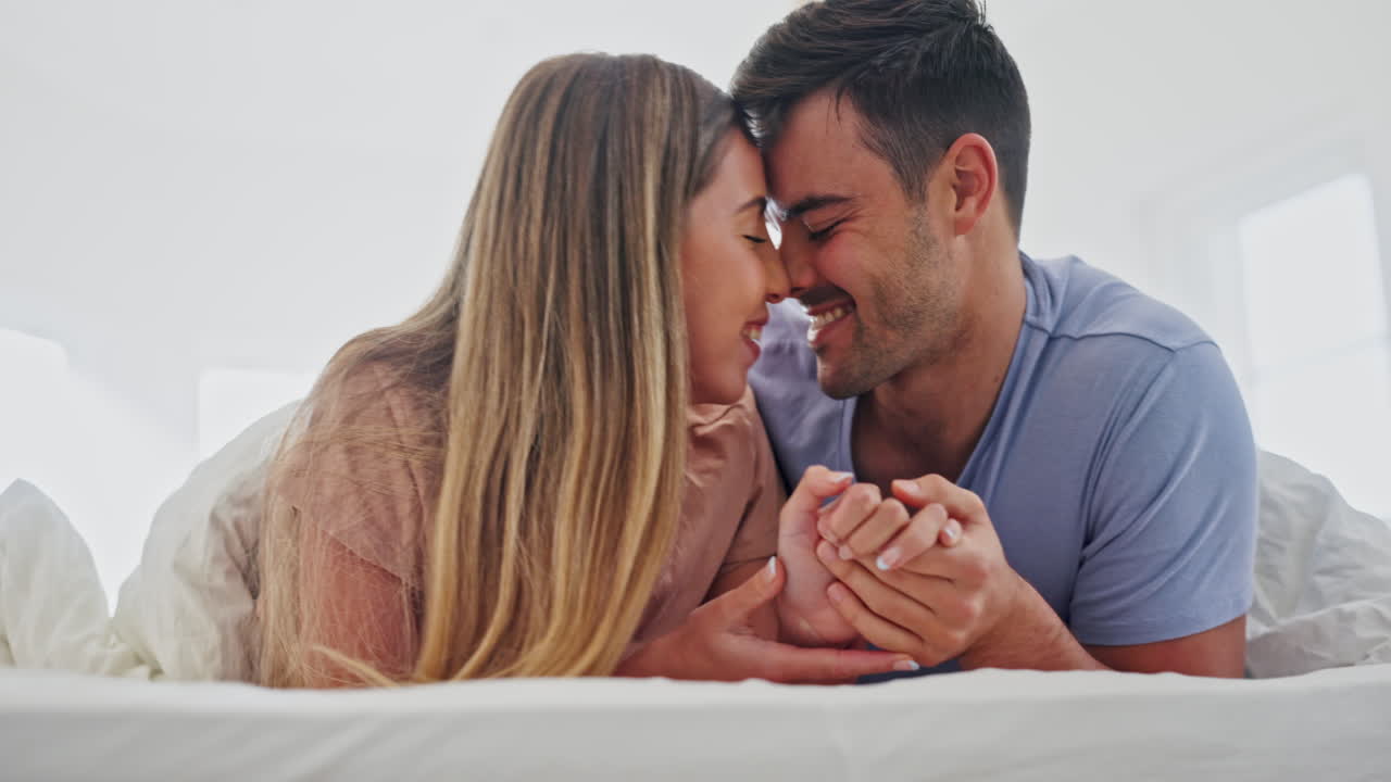 amor, felicidad y pareja tomados de la mano en la cama