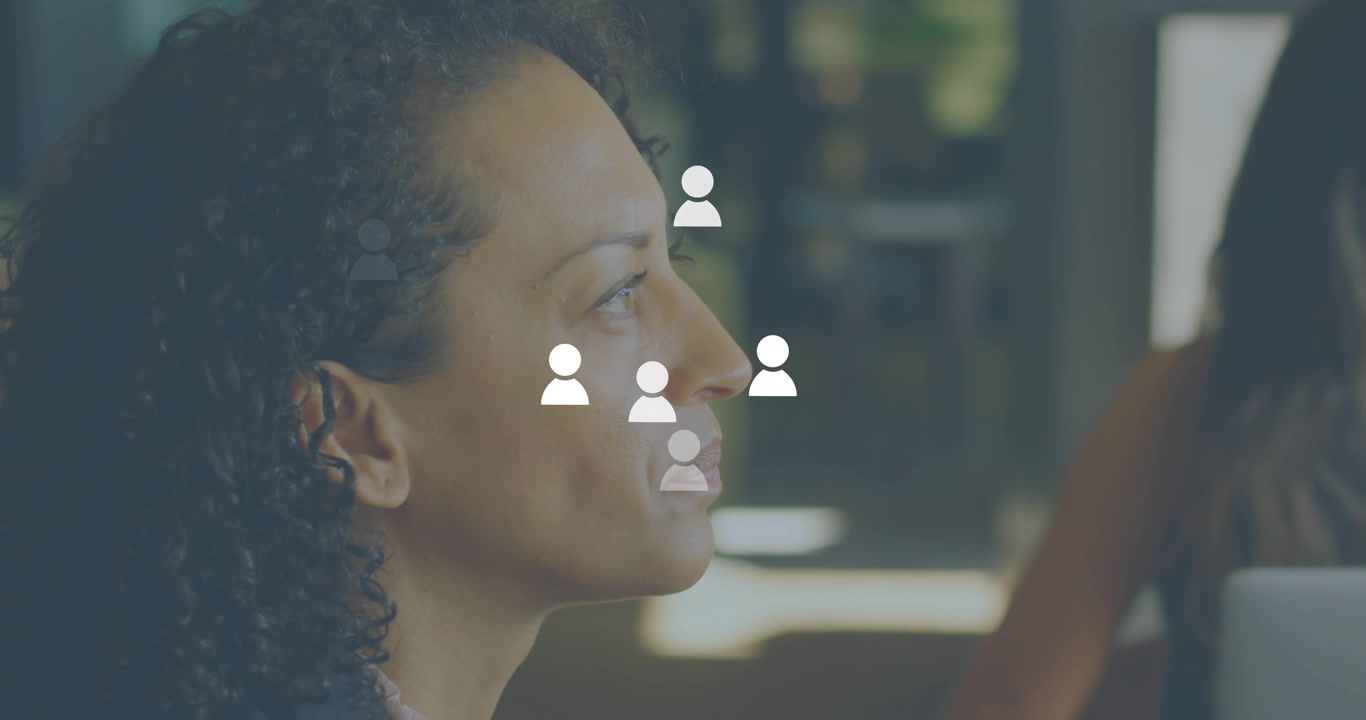 Senior woman at office desk opening mouth speaking, generating swirling avatars expanding audience