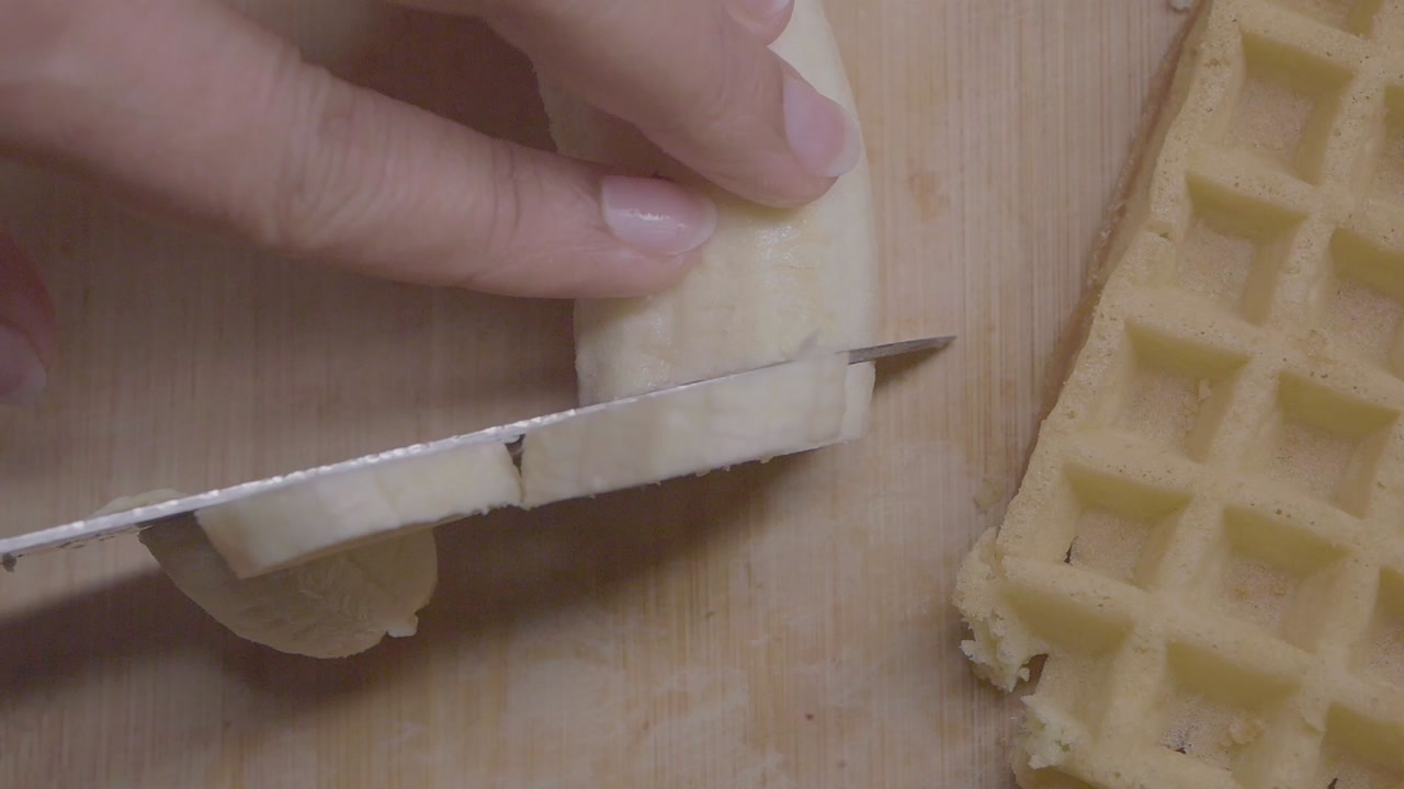 Close-up of Hand Slicing Banana on Wooden Board