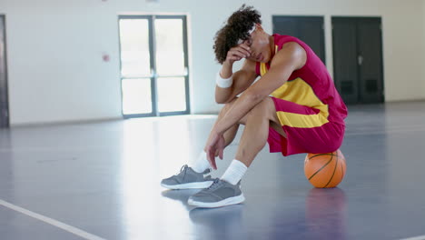 young african american man sits dejected on a basketball court