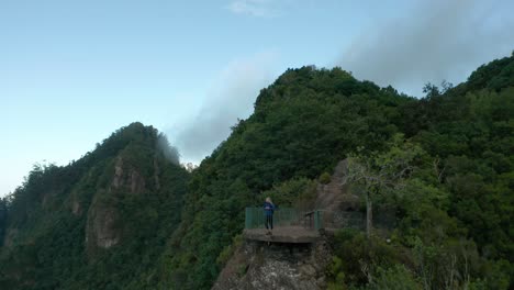 Mujer-Se-Encuentra-En-Un-Mirador-Panorámico-Rodeado-De-Montañas-Verdes