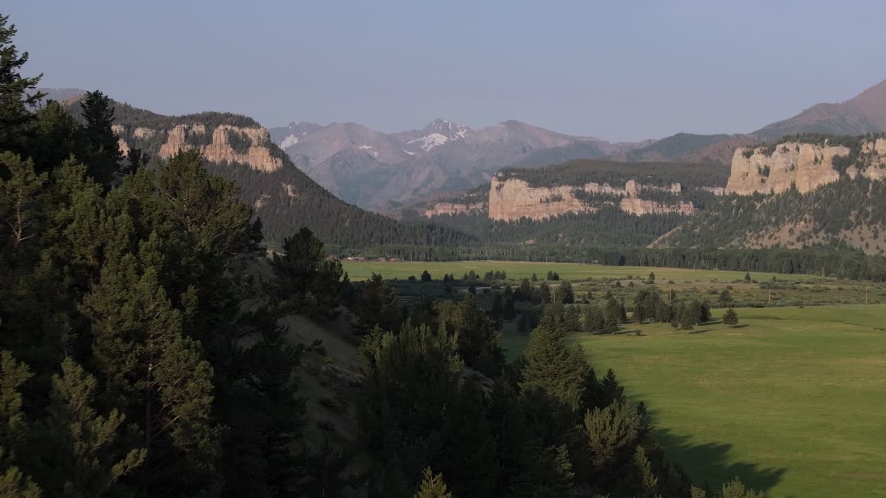 valle montañoso con vastos campos verdes y colinas boscosas bajo un cielo despejado durante el día