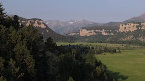 mountainous valley with vast green fields and forested hills under a clear sky at daytime
