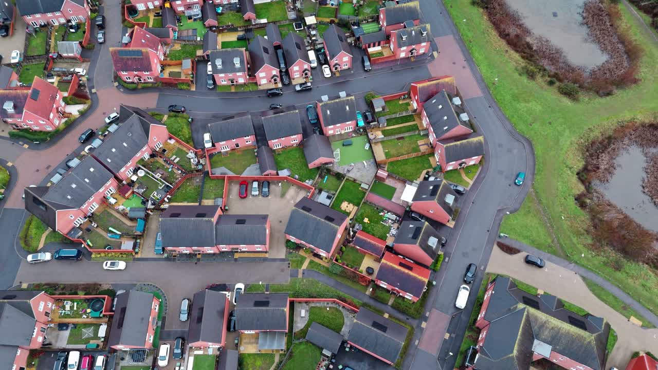 Luftoptagelser med drone over et lokalt engelsk forstadskvarter i det sydlige England ved tusmørke og solnedgang. Med befærdede veje og en rolig atmosfære med haver, træer og en dam