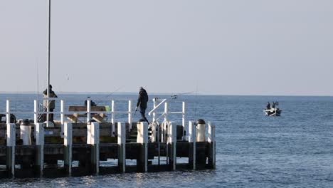 people fishing on a pier with boats nearby