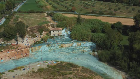 Imágenes-Aéreas-De-Drones-De-Las-Famosas-Aguas-Termales-Saturnia-Cascate-Del-Mulino-Con-Su-Agua-Azul-Cálida-Cerca-De-Grosseto-En-El-Idílico-Paisaje-De-Toscana,-Italia-Con-Colinas-Y-Olivos-Alrededor