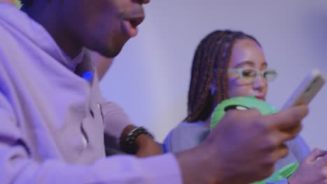 Close-Up-Studio-Shot-Of-Young-Gen-Z-Friends-Sitting-On-Sofa-Sharing-Social-Media-Post-On-Mobile-Phones-8