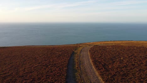 coastal sunset with wide hiker path with ocean background in north devon uk 4k - aerial drone footage