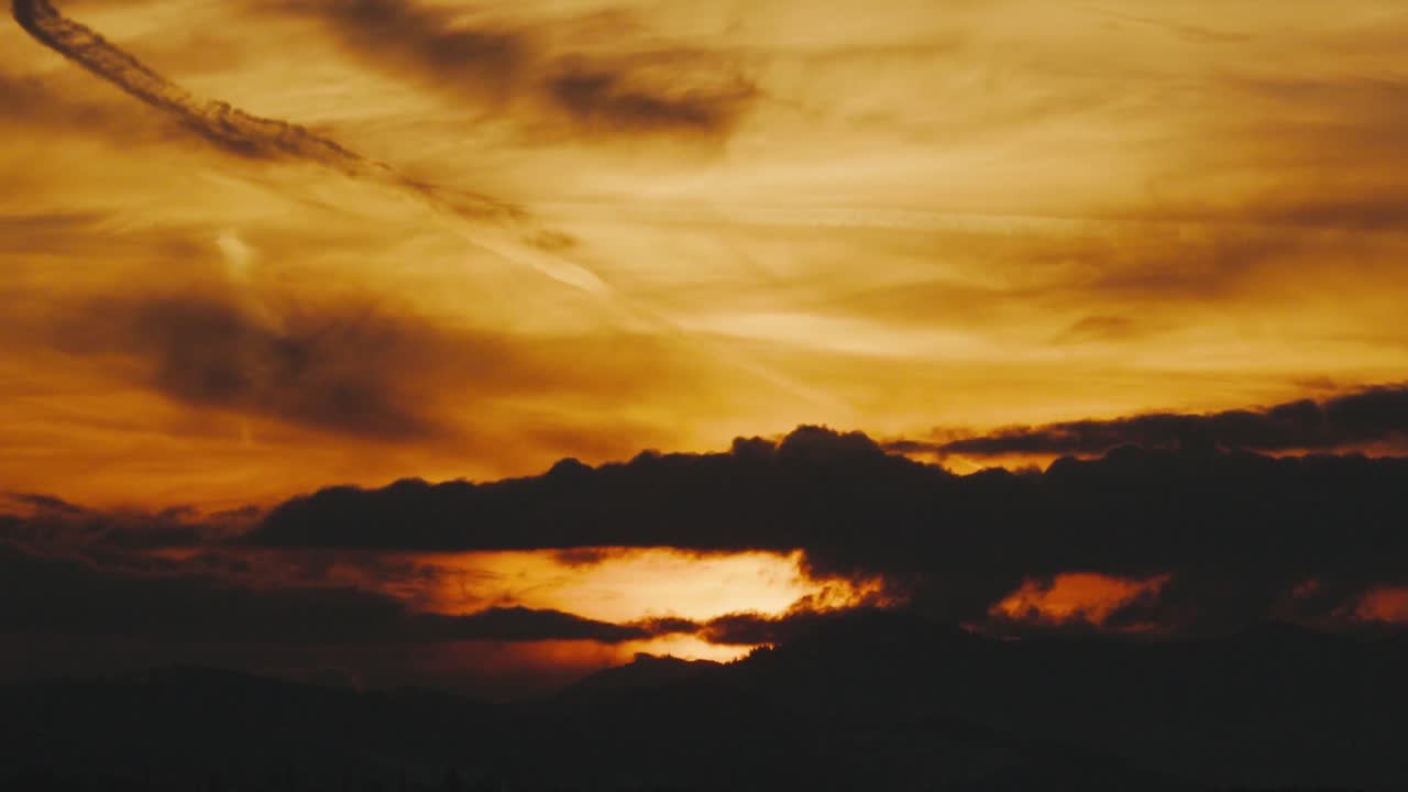 Telephoto hyperlapse of sunset with clouds and dramatic silhouette