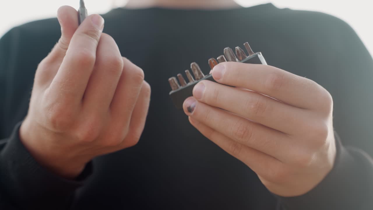 Softlit hands selecting screwdriver bits white person with painted nails, influencerstyle demonstration, backlit halo and gentle contrast, precise fingertip inspection, minimalist workshop feel, slow