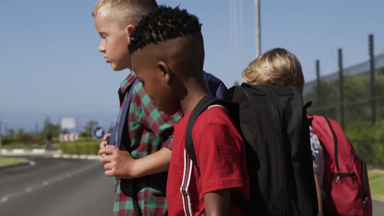 Three boys with school bags crossing the road