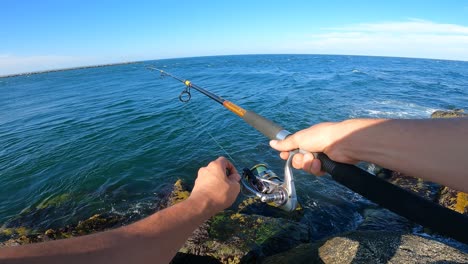 persona pescando en la costa rocosa del océano, vista pov