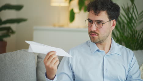 un hombre de negocios pensativo con un modelo de avión de papel.