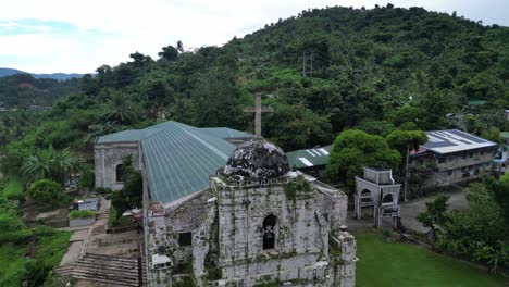 aerial orbit of idyllic, classic bato church with lush jungles and nearby rural community