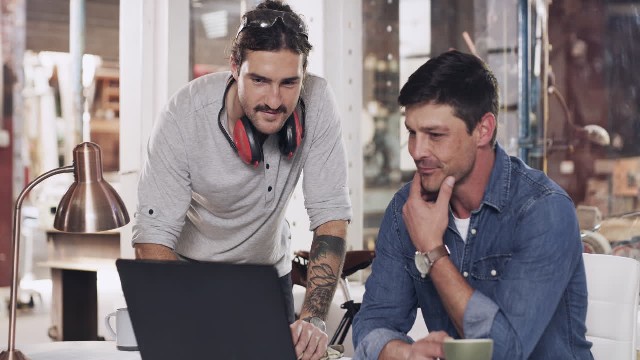 용접 작업장에서 노트북을 사용하는 두 명의 젊은 남성