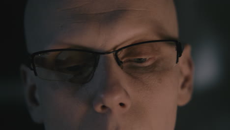 Pale bald accountant looks through the tax papers in the weird room at night