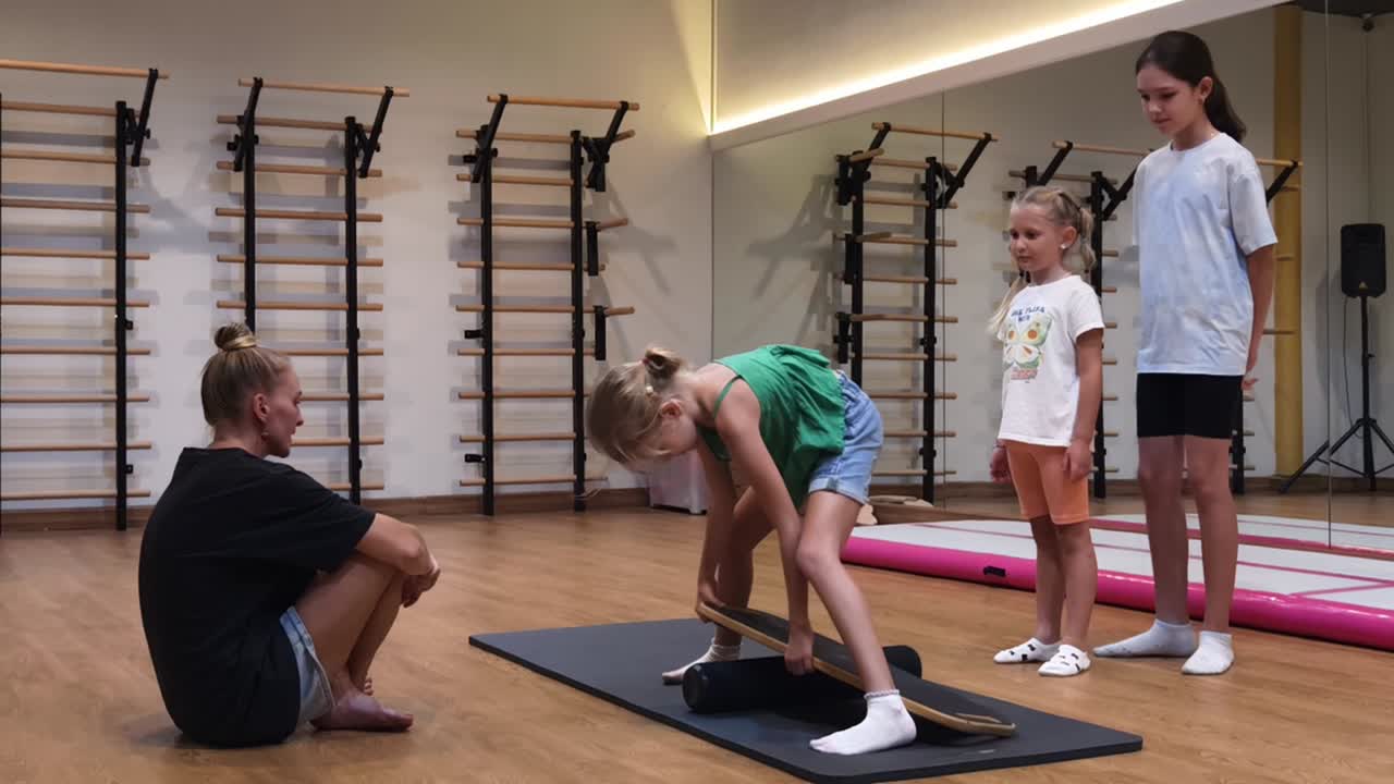 niños aprendiendo equilibrio en una tabla de equilibrio en un gimnasio