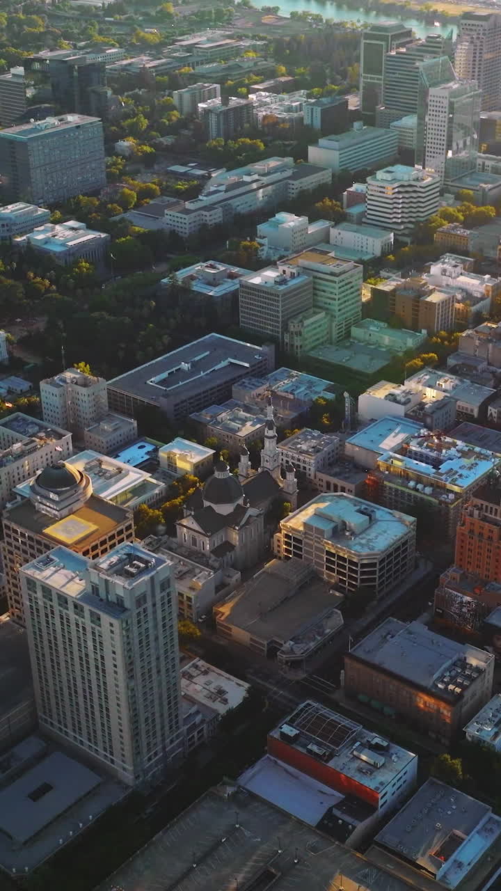 Contemporary urban architecture with lots of greenery. Amazing Sacramento city in the rays of setting sun from aerial view. Vertical video