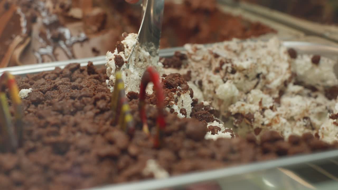 Chocolate ice cream with crushed crounchy toppings being served in a dessert station.