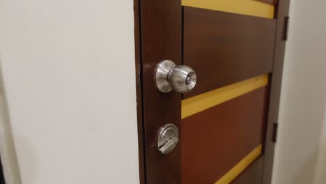 Close-up-static-shot-of-a-girl-in-jacket-locking-apartment-door's-locks