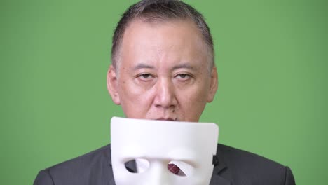 hombre de negocios japonés maduro con máscara blanca como concepto