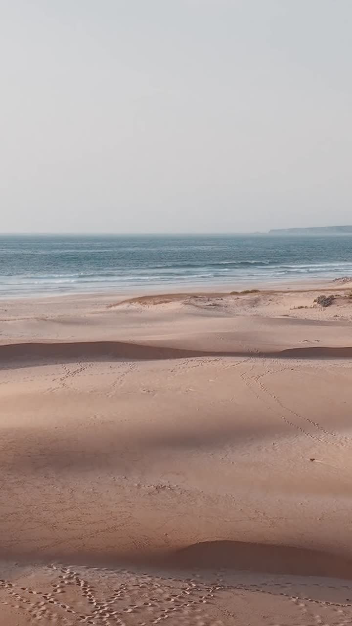 Bølger møder sand på en strand i Portugal på en solskinsdag