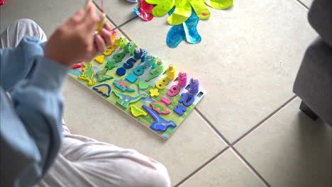 vrouw die op de vloer zit te spelen met een kleurrijke houten puzzel van baby's