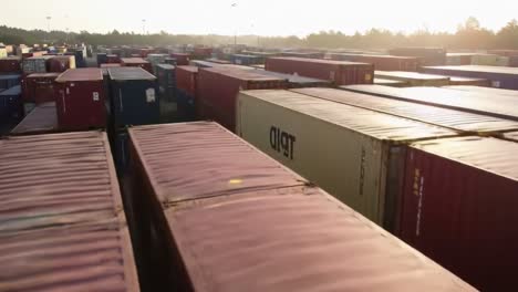 aerial view of container yard at sunset: a panoramic scene showcasing rows of shipping containers bathed in golden light in a freight logistics area