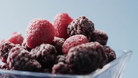 Micro-video-of-close-up-of-bowl-of-raspberries-with-copy-space-on-blue-background