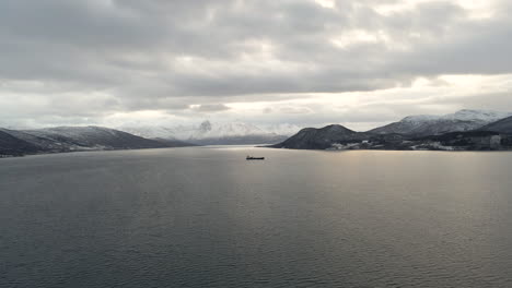 cinematic high angle view over fiord of snowy mountain range and large ship