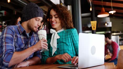 Couple-drinking-smoothie-together-with-straw-in-pub