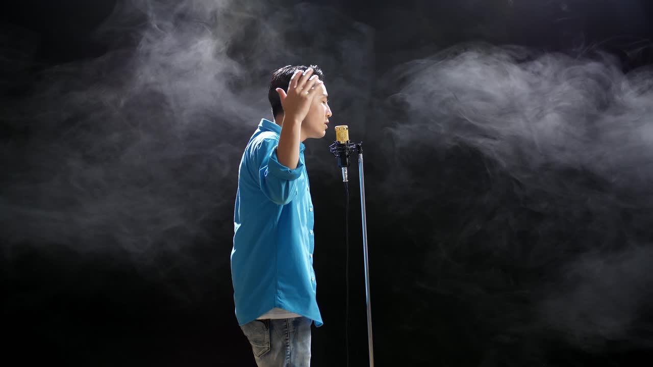 hombre cantando en un micrófono con humo