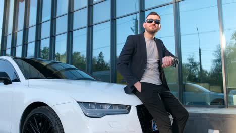 a young rich businessman in a suit standing near his luxury car a young rich businessman in a suit standing near his luxury car businessman with smart watch at modern charging station for electric vehicles