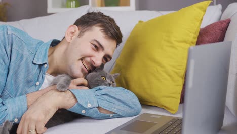 young man looking at the computer with his gray cat.