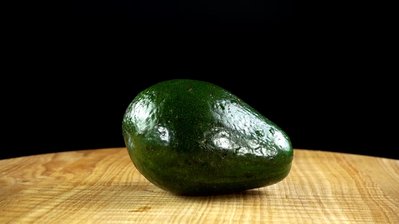 Avocado su sfondo nero. Tagliere in movimento.