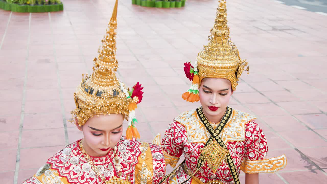 Inquadratura dall'alto di due artisti in sontuosi costumi tradizionali thailandesi e copricapi chada dorati