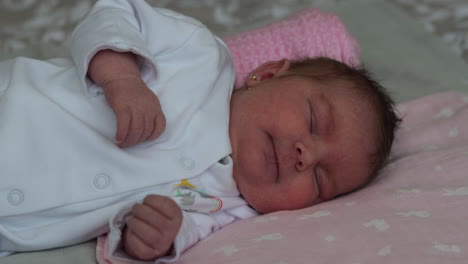 cute newborn baby girl lying on her side yawns, opens eyes as she wakes from nap