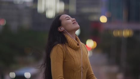 Asian-woman-wearing-earphones-listening-to-music-and-smiling