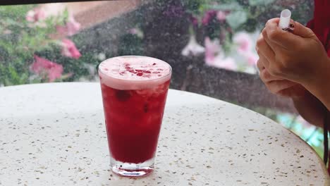 person stirring a red drink with a straw