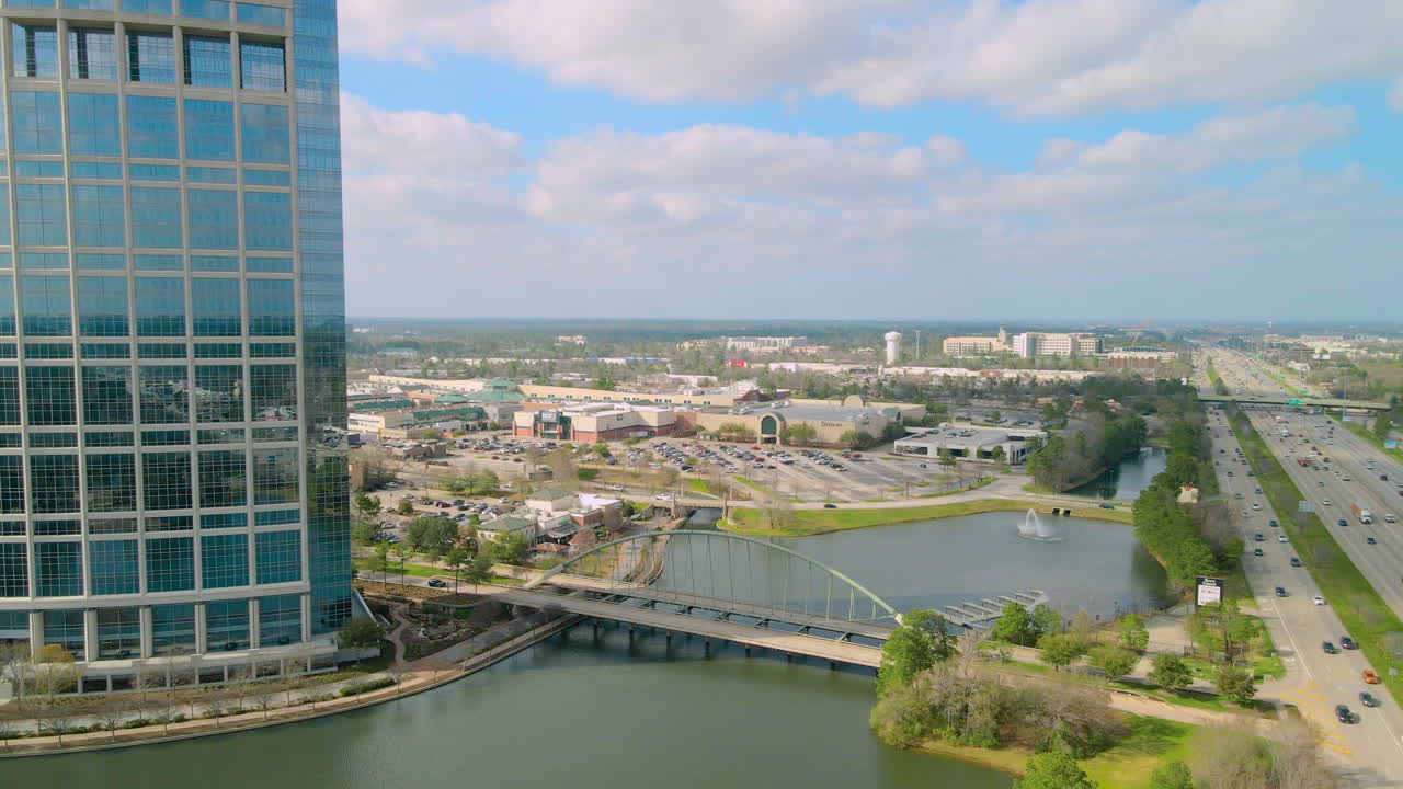Aerial view of a city with a lake, a bridge, and a mall